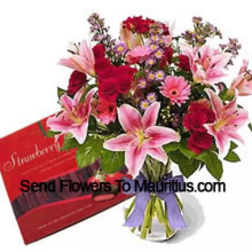 Sortierte Blumen in einer Vase und eine Schachtel Schokolade